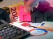 Miniature houses, Euro bills, and calculator representing real estate investment