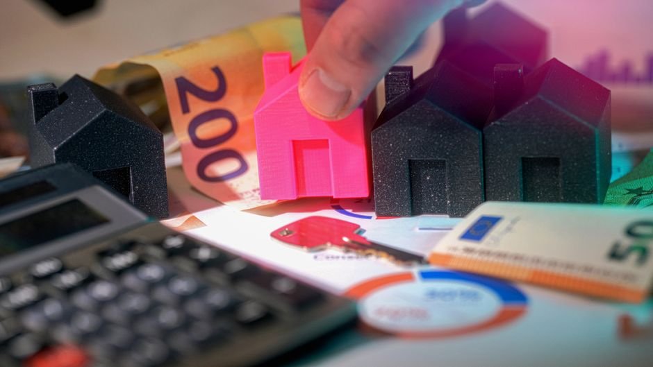 Miniature houses, Euro bills, and calculator representing real estate investment