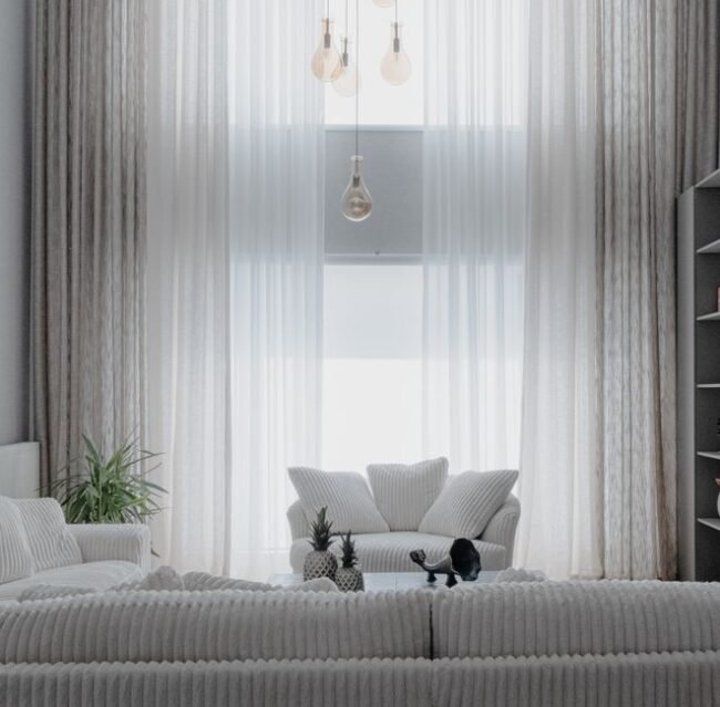 A minimalist living room with soft white sofas and large curtains, creating a cozy atmosphere