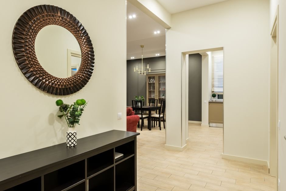 open house checklist — Interior of modern large flat with green plant on black shelf in hall illuminated with bright lamps