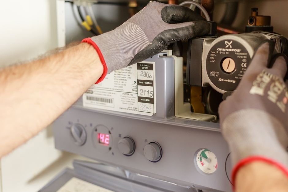 Close-up of hands adjusting a boiler system with precise instrumentation, showing maintenance work
