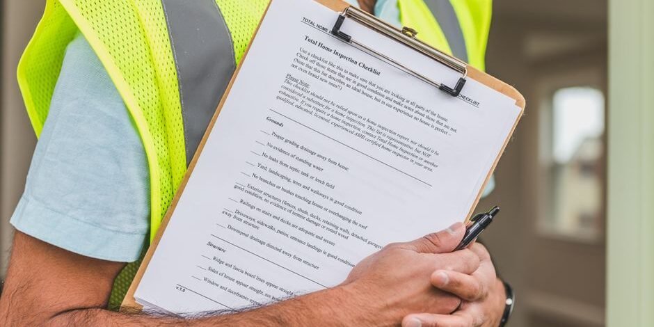 Close-up of home inspector holding a checklist on a clipboard with a pen Close-up of home inspector holding a checklist on a clipboard with a pen