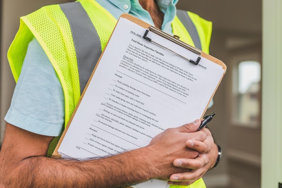 Close-up of home inspector holding a checklist on a clipboard with a pen